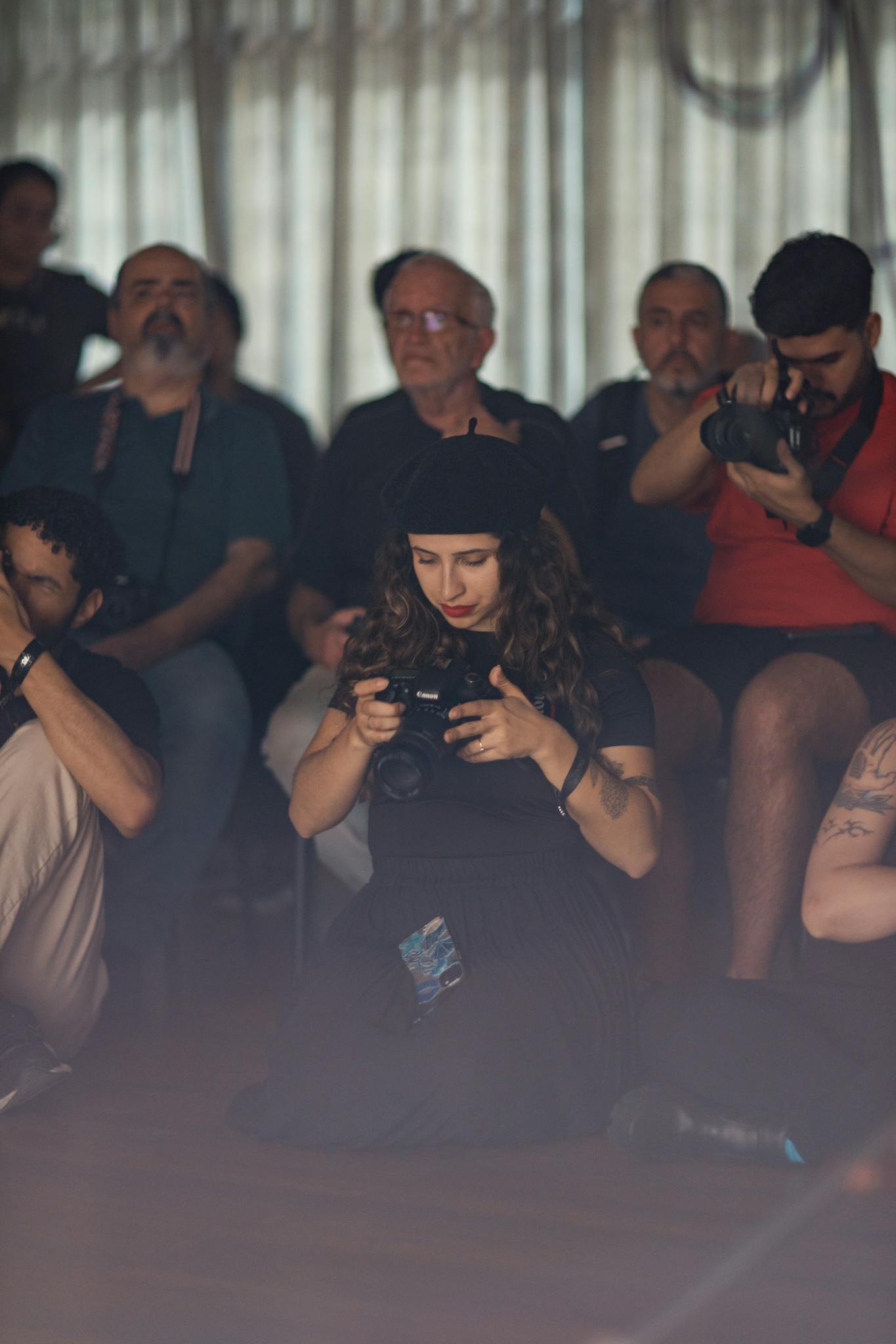 Group of photographers attentively capturing moments in a workshop setting indoors.