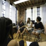 Women engaging in a panel discussion in a modern office setting, fostering an inclusive business community.
